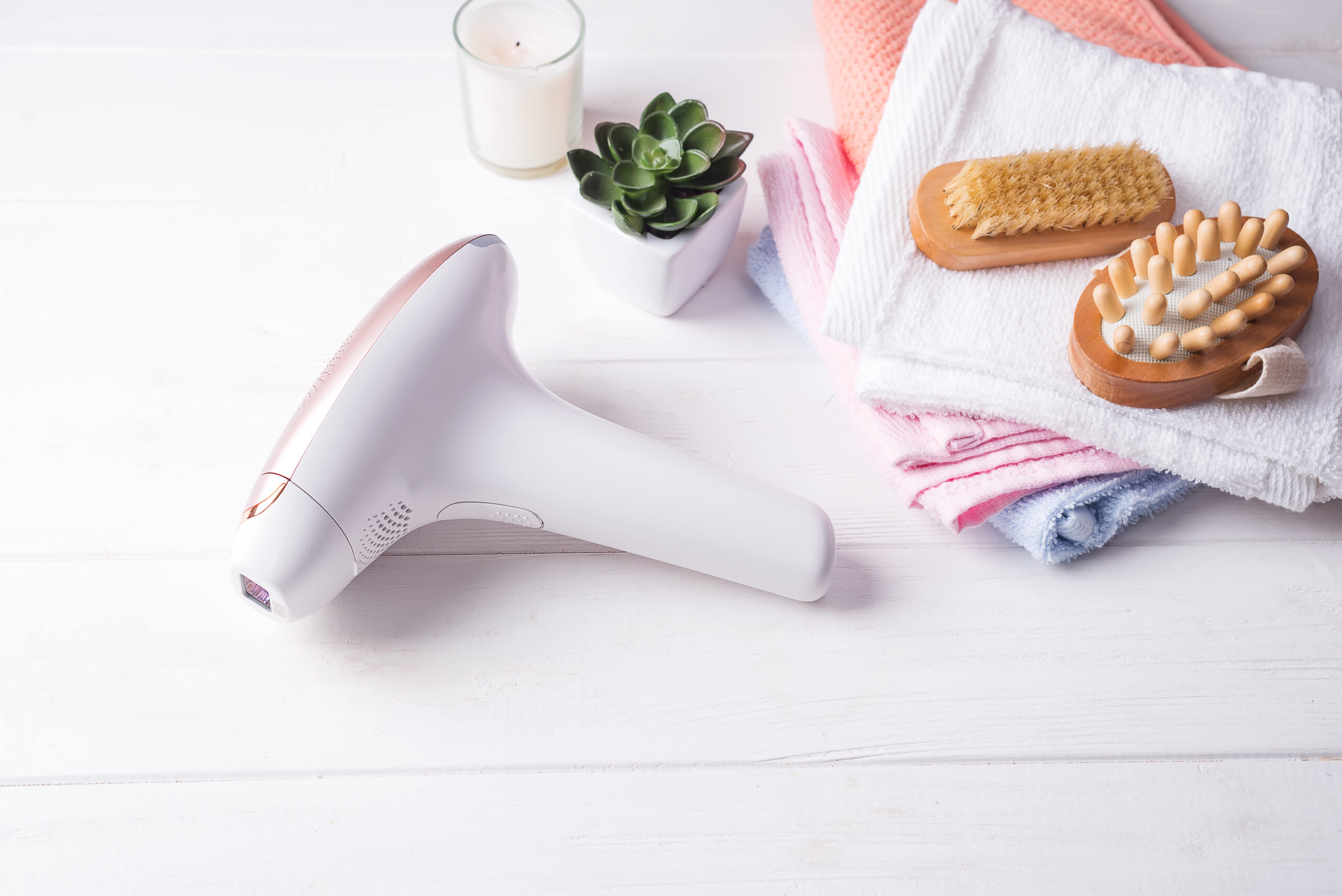 set of means of hair removal. Modern epilators in bathroom on a white wooden background.